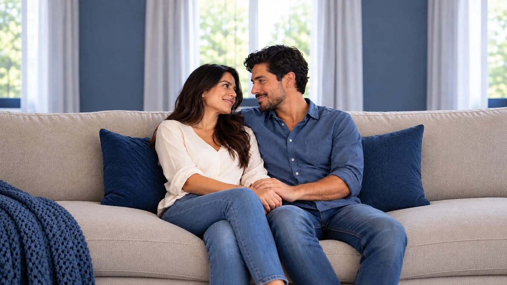 Pareja sentada en el sofá de la sala, tomados de la mano y mirándose